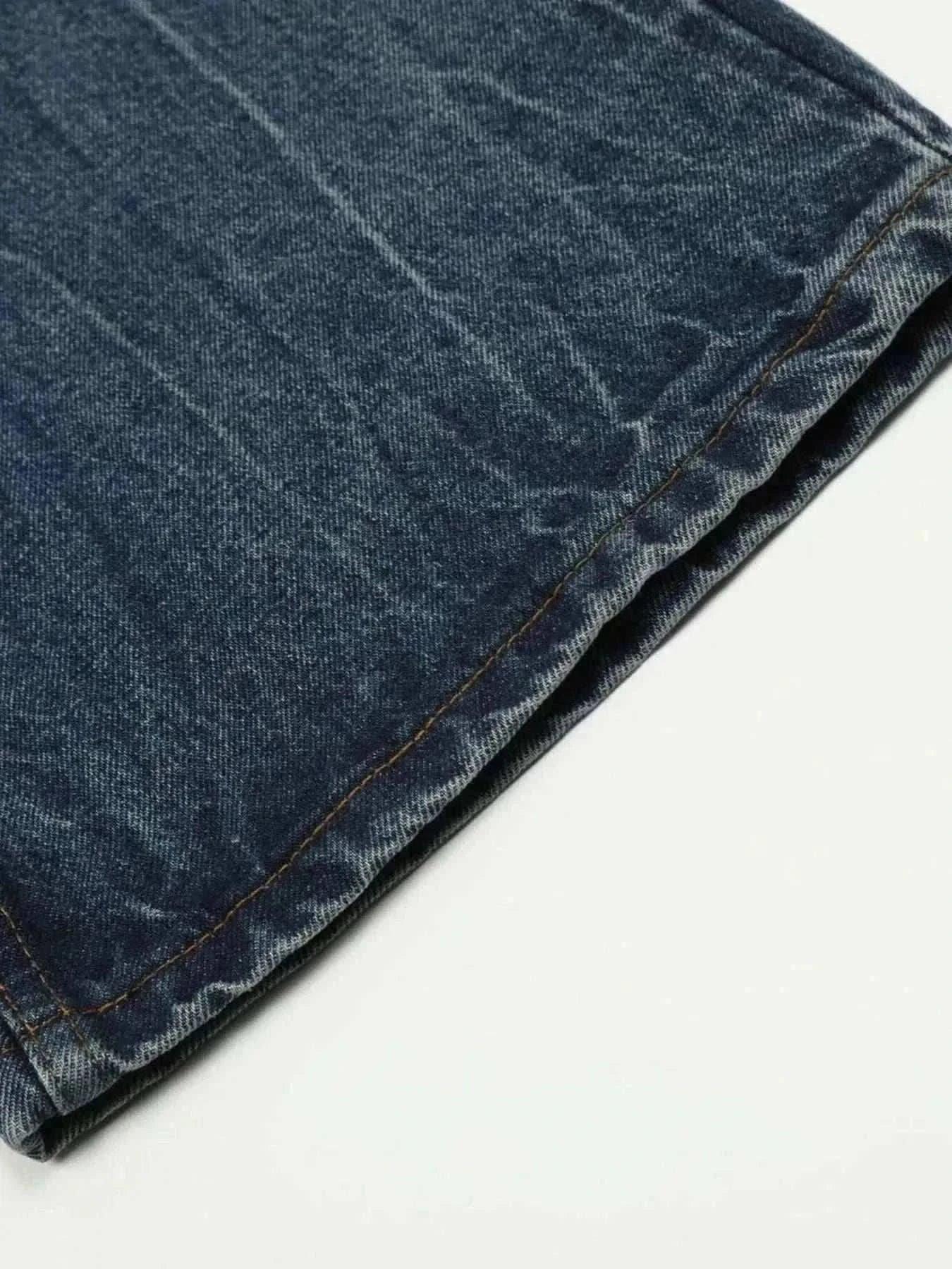 Close-up of men's wide leg jeans hem with cat's whisker faded wash detail on blue denim fabric