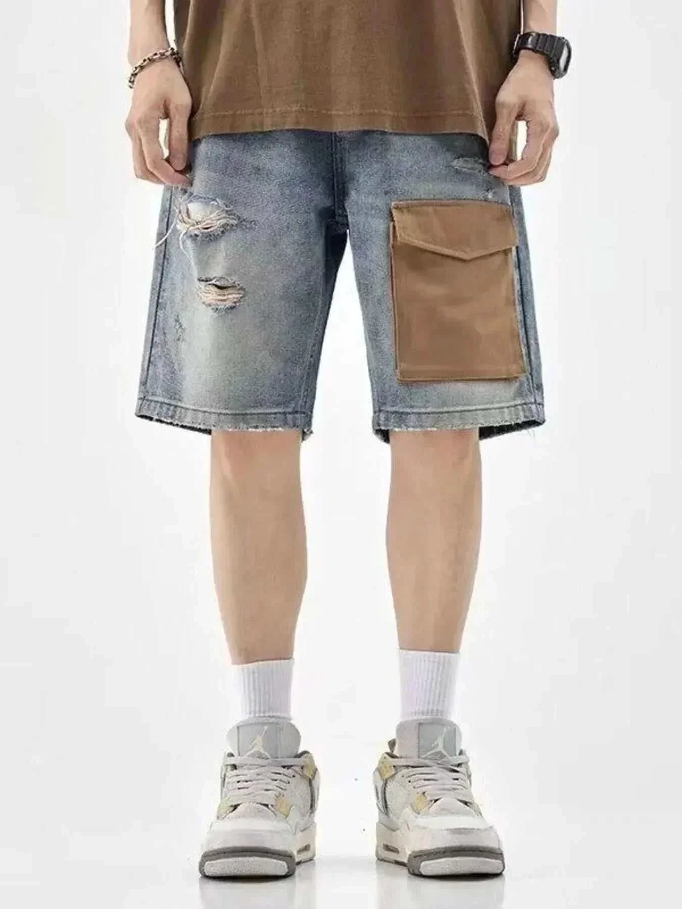 Men's distressed denim shorts with large brown utility pocket and ripped details, worn with sneakers