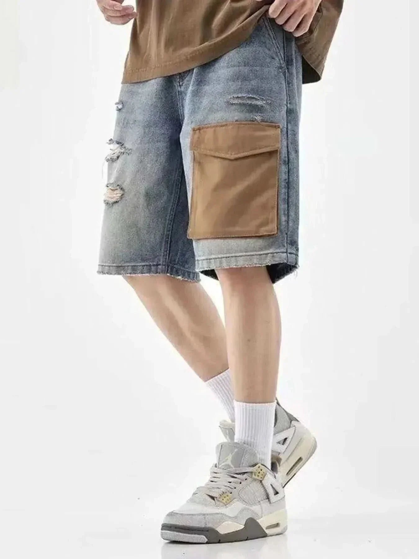 Men's distressed denim shorts with a brown utility pocket and ripped details worn with white sneakers and socks