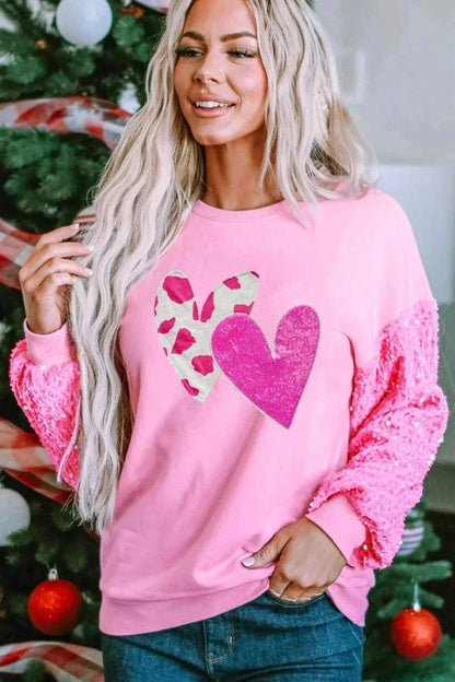 Woman wearing pink Valentine’s Day sequin heart long sleeve sweatshirt with textured sleeves and two heart designs on front