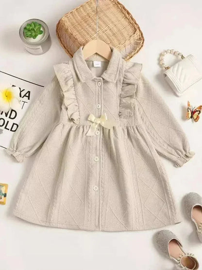 Beige children's ruffled bow collar dress with long sleeves and button front, made of soft polyester fabric.