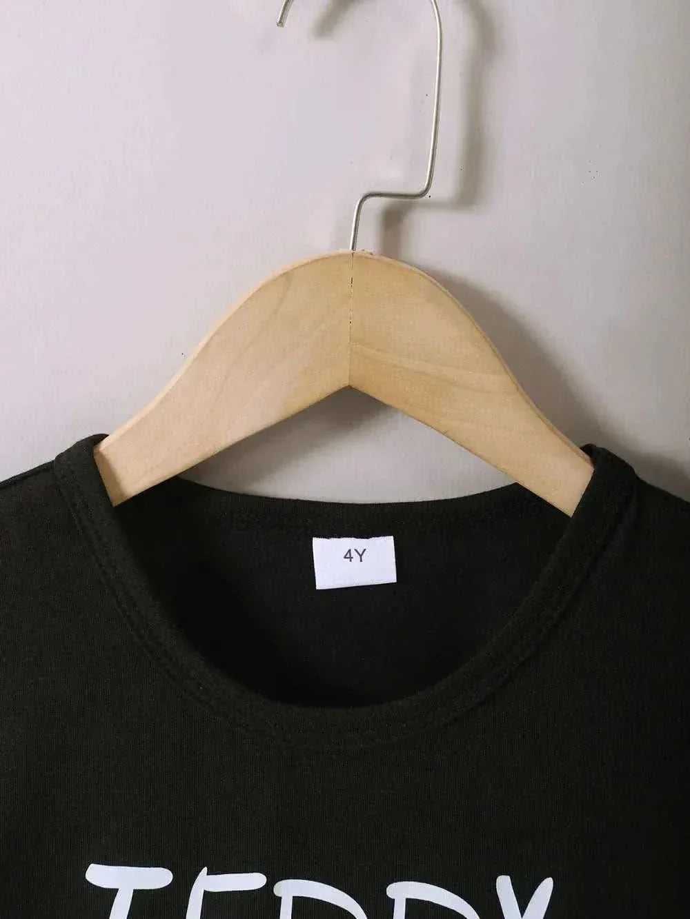 Children's black round neck top with teddy bear print hanging on wooden hanger size 4Y