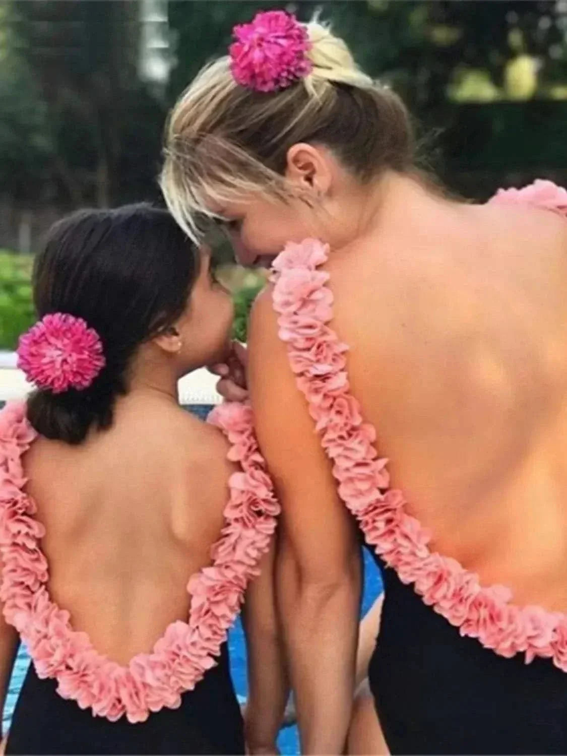 Backless matching mother daughter swimsuits with pink petal straps and floral hair accessories by the pool